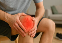 Ból w kolanie. Mężczyzna trzymający się za kolano