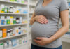 Kobieta w ciąży w aptece, szukająca suplementów