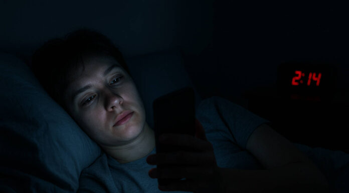 Zaburzenia snu – przyczyny i skuteczne metody leczenia Kobieta z zaburzeniami snu przeglądająca telefon w nocy w łóżku