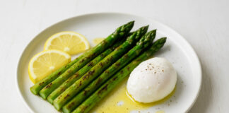Właściwości zdrowotne szparagów – z czym je łączyć? Talerz z grillowanymi szparagami na maśle, z jajkiem i plasterkami cytryny