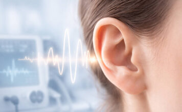 Szumy w uszach, skąd się biorą i kiedy wymagają diagnostyki? Zbliżenie na ludzkie ucho, w tle fale świadczące o szumach