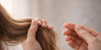 Wypadanie włosów, a niedobory witamin i mikroelementów Kobieta trzymająca włosy, w kontekście ich wypadania - obok kropla suplementu (symbolicznie)