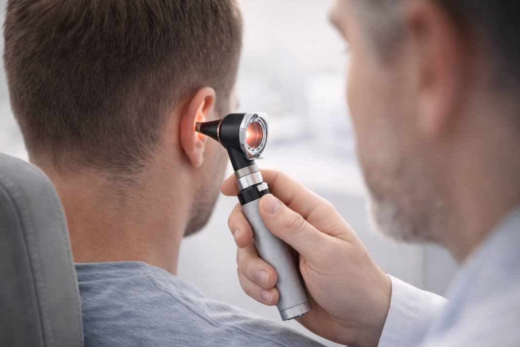 Lekarz badający ucho pacjenta otoskopem