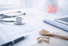 Rysunek tarczycy w tle, na stole stetoskop, wyniki badań, leki na tarczycę