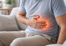 Mężczyzna trzymający się za brzuch, czerwona fala wskazująca ból, w kontekście wrzodów żołądka