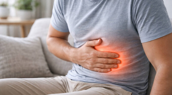 Wrzody żołądka – objawy przyczyny i ich leczenie Mężczyzna trzymający się za brzuch, czerwona fala wskazująca ból, w kontekście wrzodów żołądka