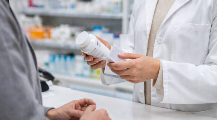 Farmaceuta trzymający lek i pacjent przy ladzie w kontekście zmieniania dawki leku