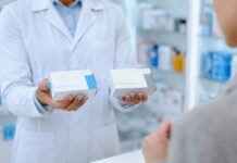 Farmaceuta trzymający w dłoniach dwa leki - oryginalny i generyczny. Grafika bez marek